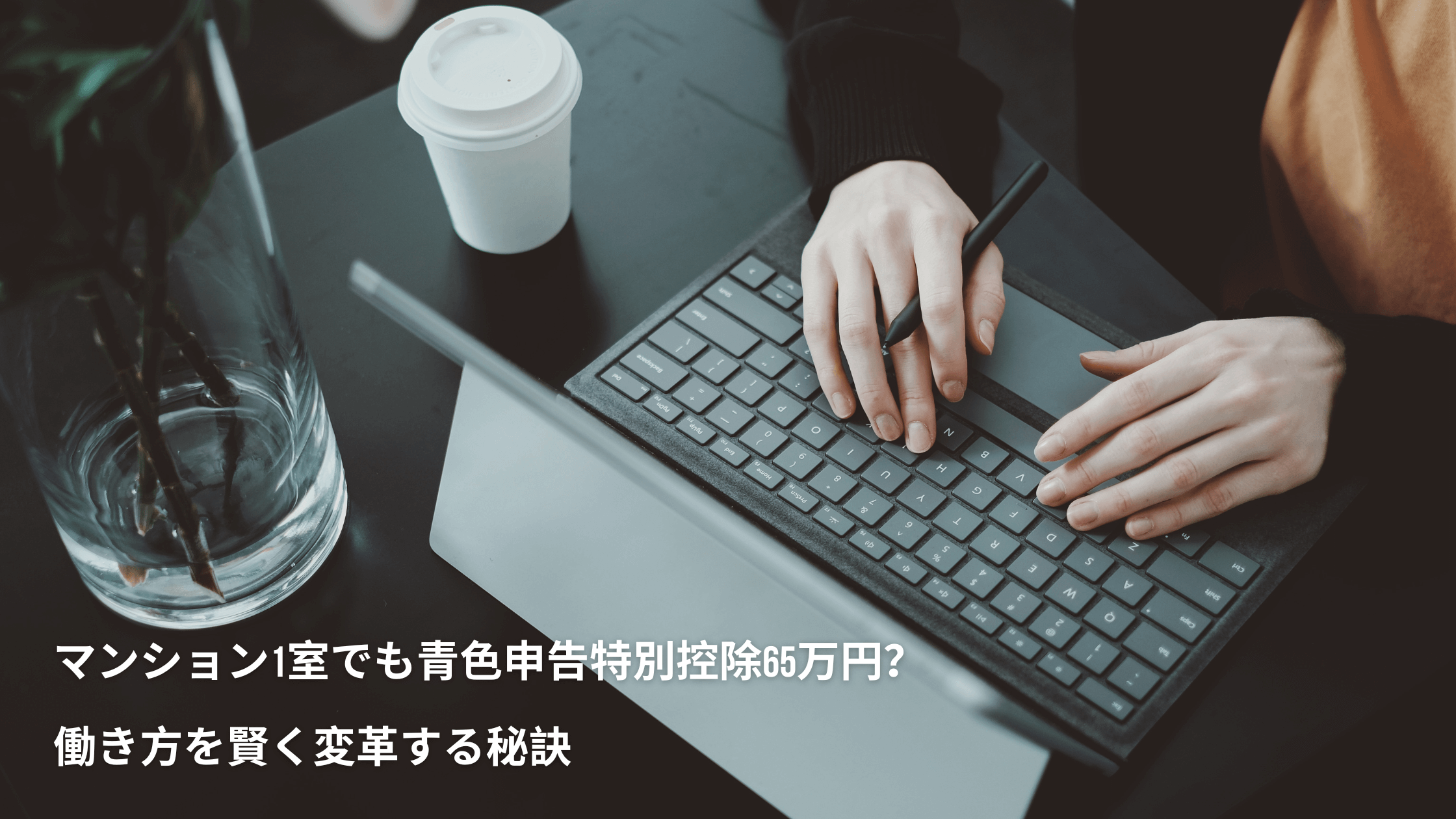 机上でノートパソコンのキーボードで入力している人の手。左下に記事のタイトルが掲載。